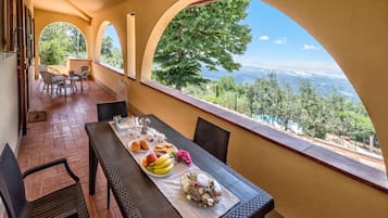 A terrace with a table set for breakfast, overlooking a scenic landscape.