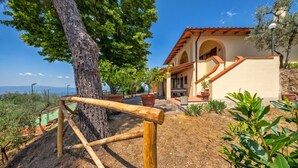Eine Villa mit einer Holzpergola, einer Steinmauer und Meerblick.