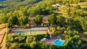 Eine Villa mit Tennisplatz, Schwimmbad und üppiger Bepflanzung.