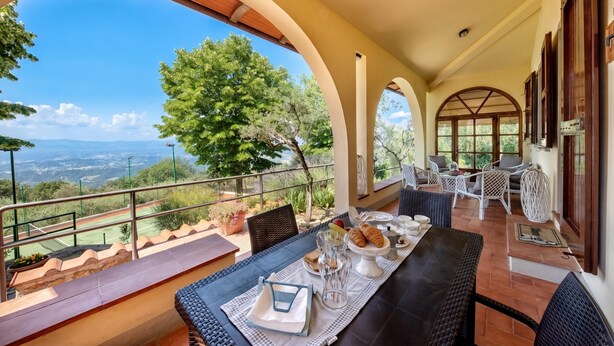 Eine Terrasse mit Esstisch, gedeckt für das Frühstück, mit Blick auf eine malerische Landschaft.