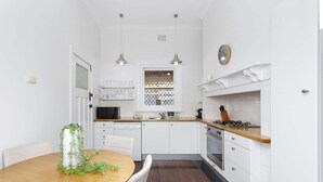 Una cocina moderna con armarios blancos, una mesa de comedor de madera e iluminación colgante.