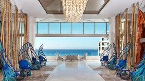 A modern interior with a view of the ocean, featuring hanging chairs and a central seating area. - Garza Blanca Spa & Resort - Los Cabos (Cabo San Lucas)