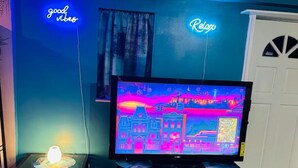 A living room with a TV, a fireplace, and neon signs on the wall. - This special place is close to everything, making it easy to plan your visit.  (Smyrna)