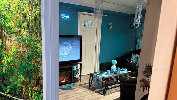 A living room with a TV, a fireplace, a dining area, and a view of a garden through a glass door. - This special place is close to everything, making it easy to plan your visit.  (Smyrna)