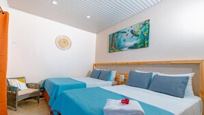 A hotel room with two beds, a wooden headboard, a wall clock, and a tropical-themed painting. - Mountain Top Park Hotel (Quepos)