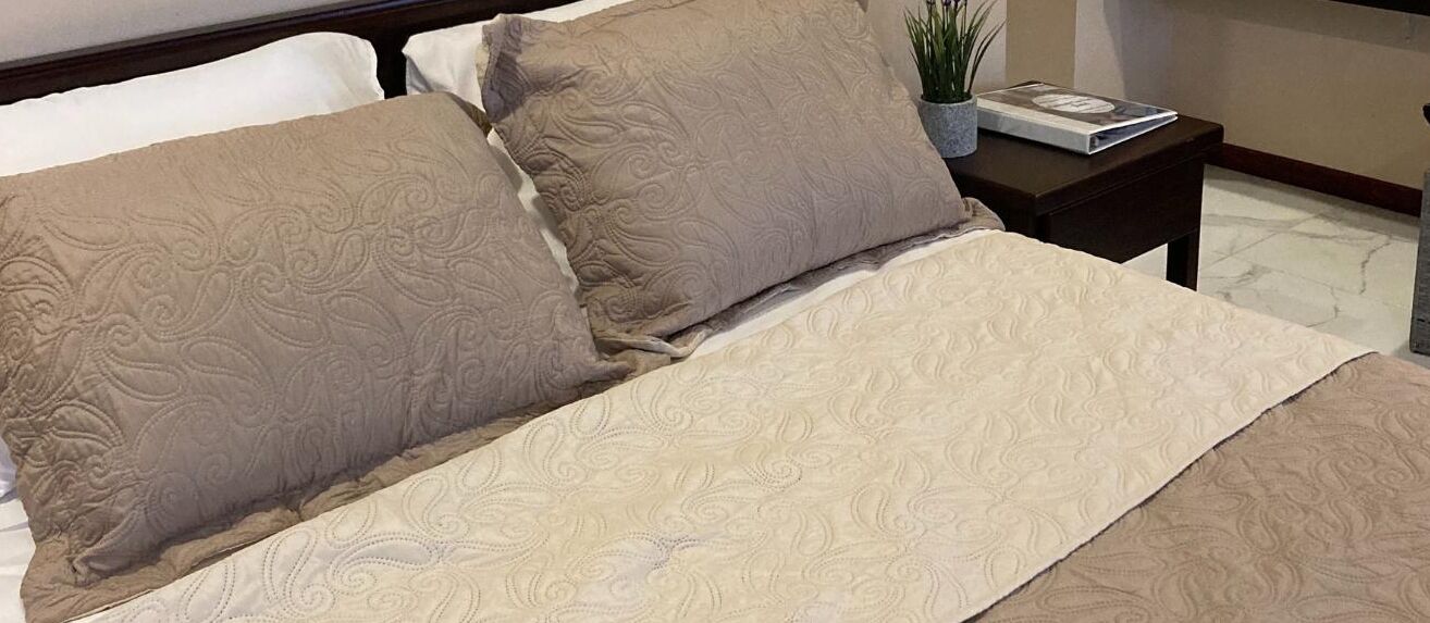 Un lit bien fait, avec une couvre-lit à motifs et deux oreillers.