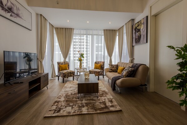 Un salon moderne avec un canapé, des fauteuils, une table basse et un téléviseur.