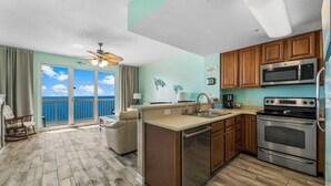 A kitchen with a view of the ocean, wooden cabinets, stainless steel appliances, and a ceiling fan. - Seychelles 2103 (Panama City Beach)