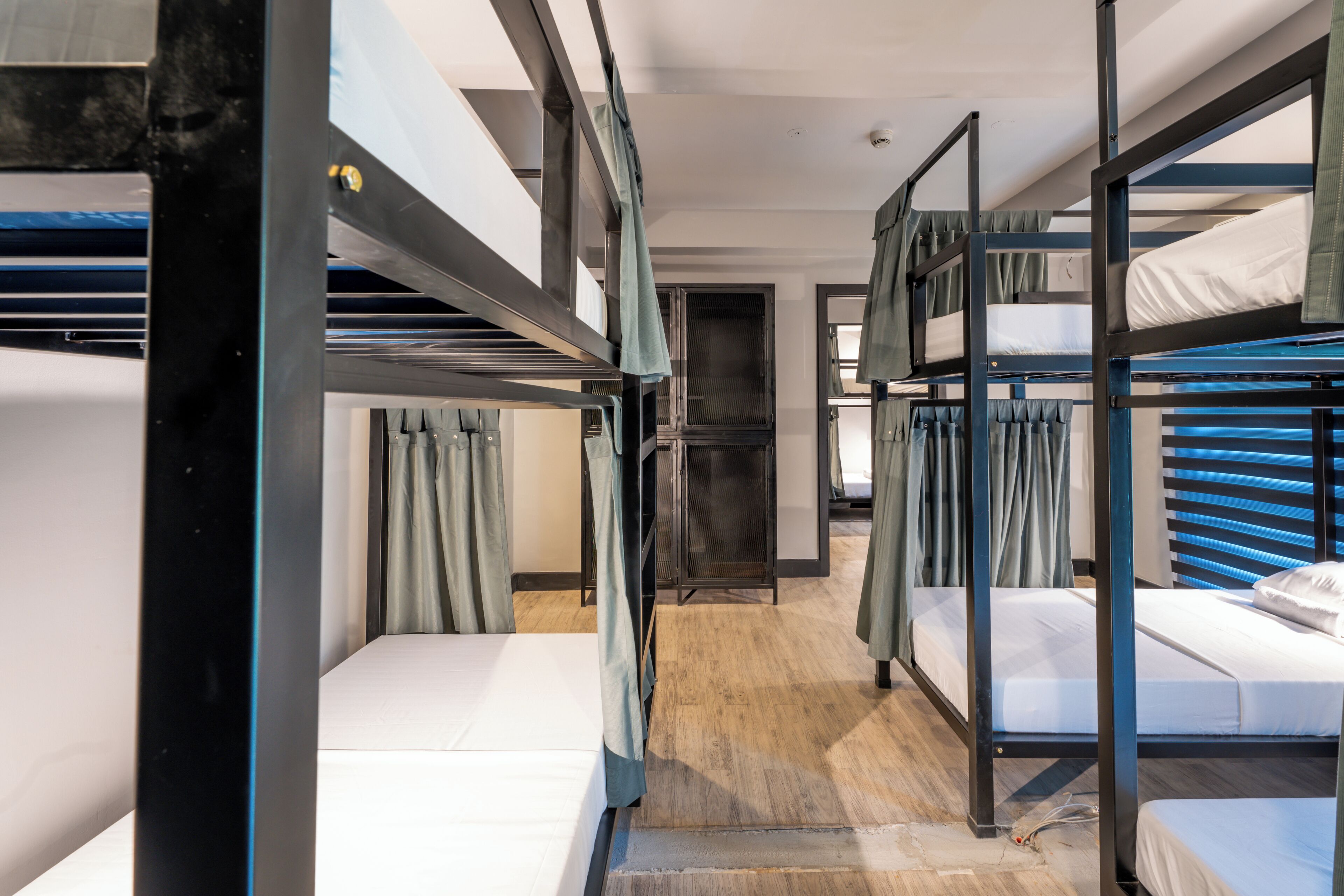 Habitación con literas, suelo de madera, una puerta y cortinas.