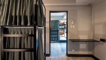 A room with bunk beds, a small desk, and a door leading to another room.