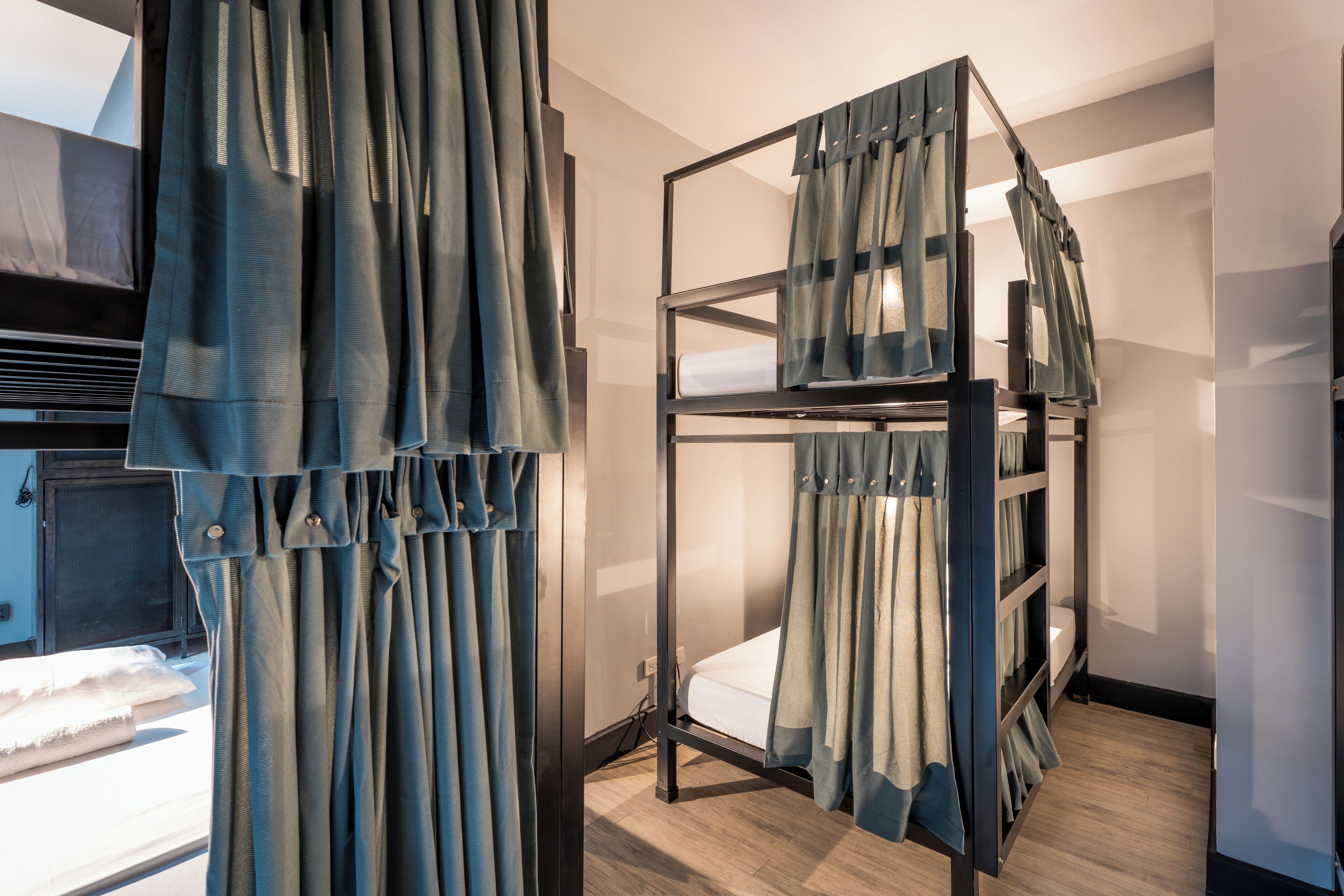 A bunk bed with curtains, a wooden floor, and a window.