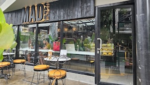 A cafe with outdoor seating, a glass door, and a sign reading "MAD". - Mad Monkey Manila (Makati)