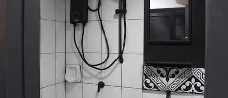 Une salle de bain avec un lavabo blanc, un robinet noir et une douchette fixée au mur.