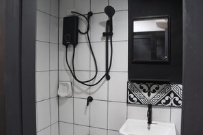Een badkamer met een wit wastafelmeubel, een zwarte kraan en een handdouche aan de wand.