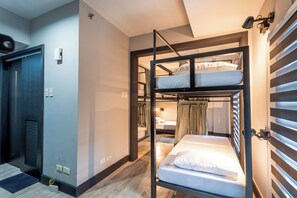 Een slaapkamer met stapelbed, een deur, een stopcontact en een raam met gordijnen.