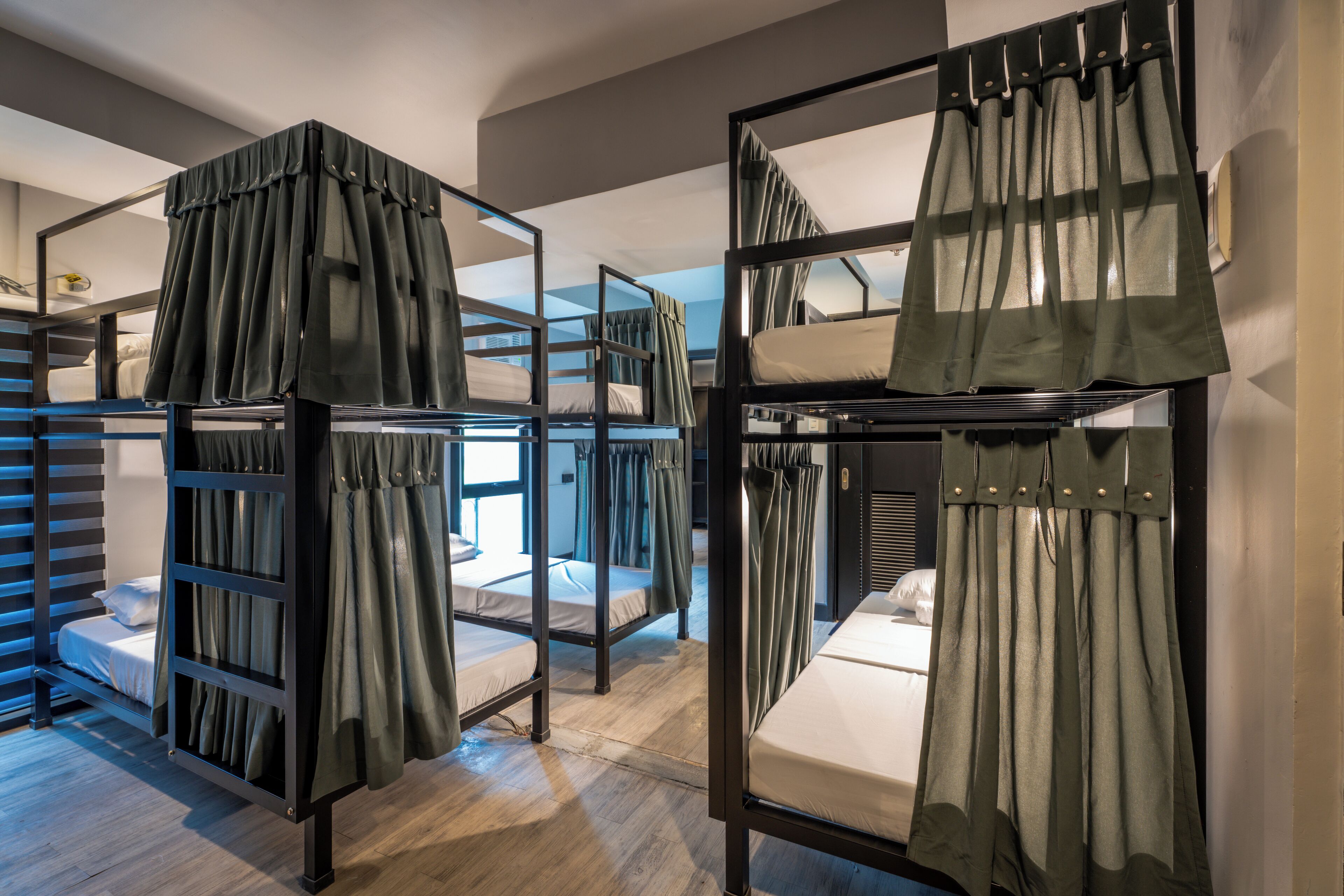 Bunk beds with curtains, wooden flooring, and a window with daylight.