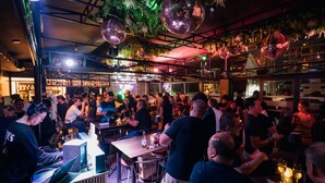 A crowded bar with people socializing, a DJ booth, and disco balls. - Mad Monkey Manila (Makati)