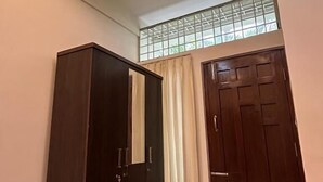 Un couloir avec une armoire en bois sombre, une porte et une fenêtre avec des rideaux.