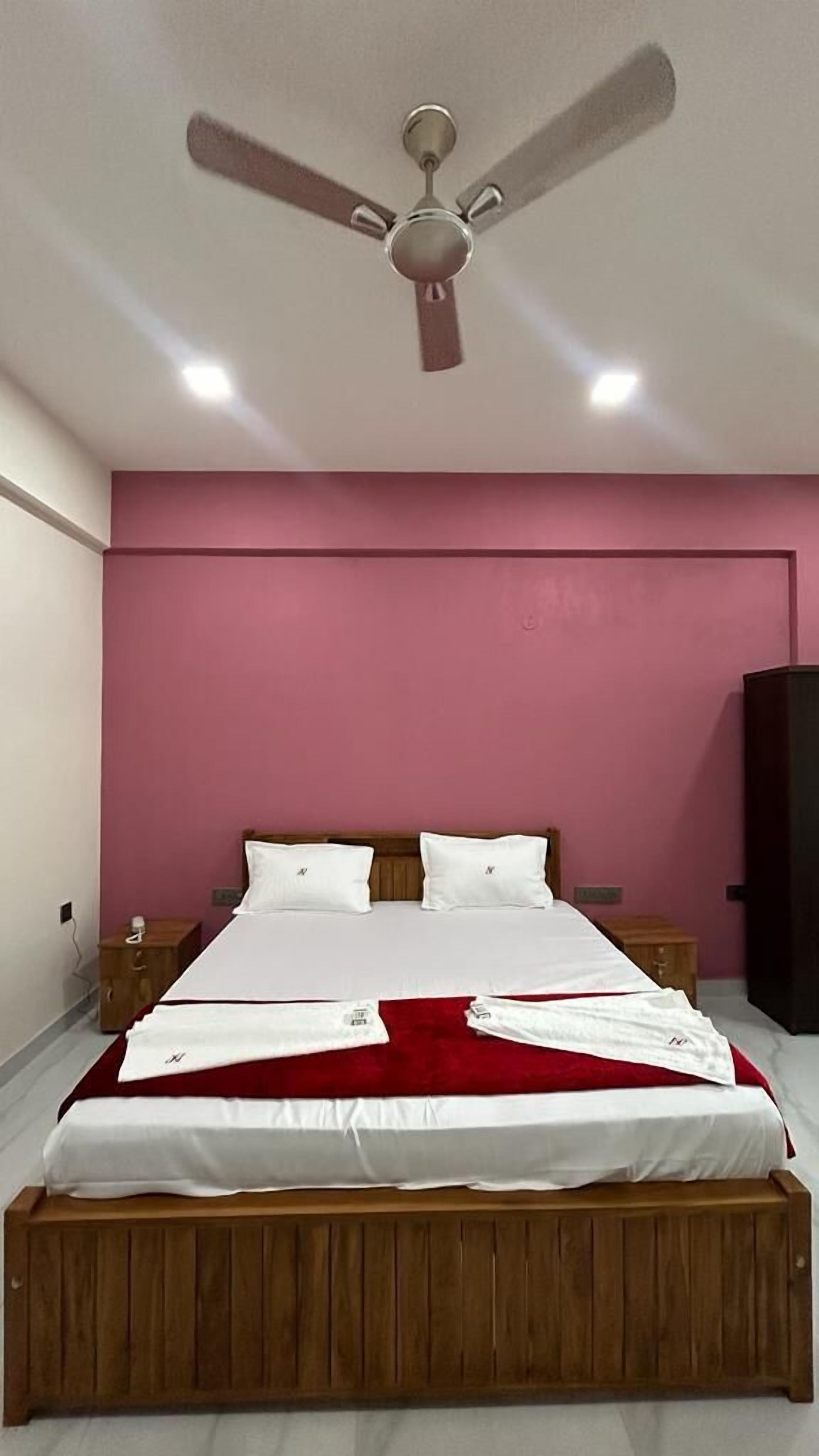 A bedroom with a bed, a ceiling fan, and a pink wall.