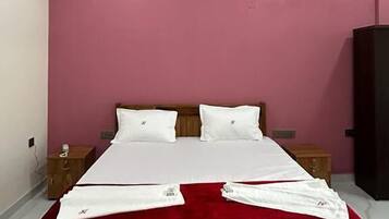 A bedroom with a bed, a ceiling fan, and a pink wall.