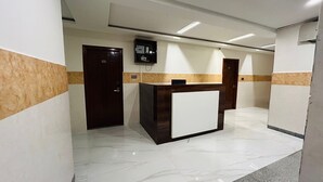 Un hall d’hôtel avec un comptoir d’accueil, une caméra de surveillance et une porte portant l’inscription « 103 ».