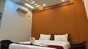 Une chambre moderne avec un lit en bois, une literie blanche, un ventilateur de plafond, un éclairage encastré et un appareil de climatisation.