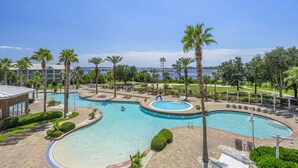 A resort with multiple swimming pools, palm trees, and a view of the water. - Reflections at Bay Point Unit 412 (Panama City Beach)