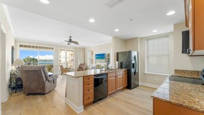 A spacious kitchen with wooden cabinets, a granite countertop, and a large island. - Reflections at Bay Point Unit 412 (Panama City Beach)