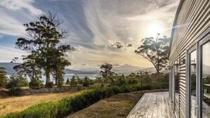 A modern building with a wooden deck overlooking a natural landscape with trees and mountains. - NewHaven, private retreat overlooking Dover Bay (Dover)