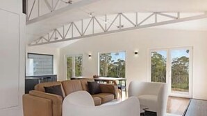 A spacious living area with a large sofa, a white armchair, and a dining table. - NewHaven, private retreat overlooking Dover Bay (Dover)