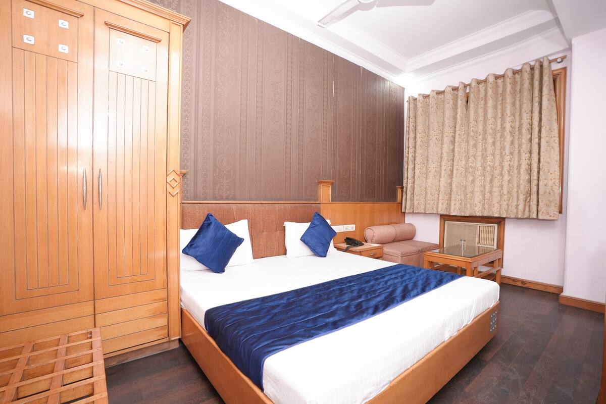 Habitación de hotel con una cama grande, armario de madera y una pequeña mesa con una silla.