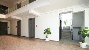 A spacious indoor area with a wooden floor, a staircase, and potted plants. - Hotel Royal Galaxy (Gurugram)