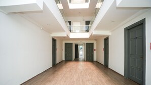 A spacious corridor with wooden flooring, glass railings, and doors leading to rooms. - Hotel Royal Galaxy (Gurugram)