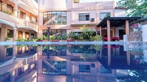 A modern building with a reflective pool, balconies, and potted plants. - Dinah's Tourist Inn Puerto Princesa (Puerto Princesa)