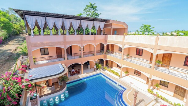 A multi-story hotel with a central swimming pool, outdoor seating, and balconies. - Dinah's Tourist Inn Puerto Princesa (Puerto Princesa)