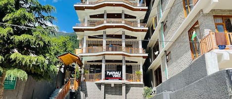 Un hotel de varios pisos con un letrero llamativo que dice "Manali Vibes".