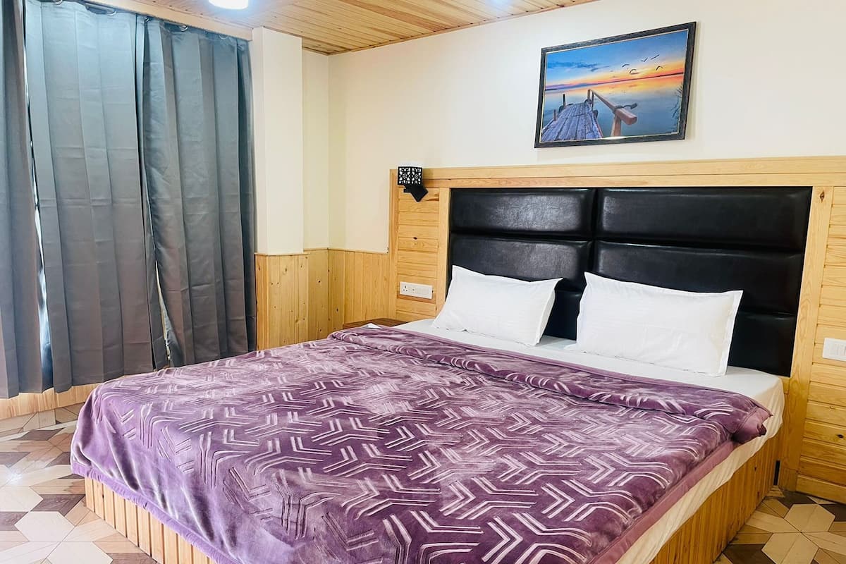 Une chambre à coucher avec un lit, une tête de lit, un tableau et une fenêtre avec des rideaux.