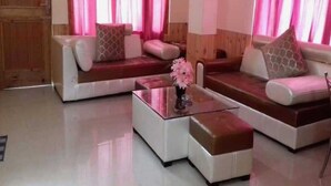 A modern living room with a sectional sofa, a glass coffee table, and a decorative vase. - Antriksh Cottage Manali (Manali)