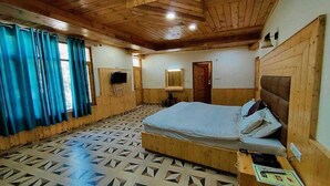A wooden room with a bed, a small table, and a TV. - Antriksh Cottage Manali (Manali)