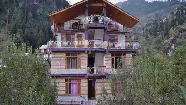 A multi-story wooden chalet with balconies, set in a mountainous area. - Antriksh Cottage Manali (Manali)