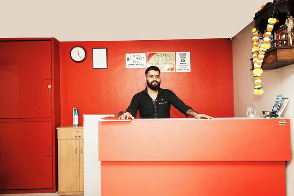 A hotel reception desk with a clock, a wooden cabinet, and a wall with hotel signs. - Harihara Residency Comfort Andheri East, Mumbai (Mumbai)