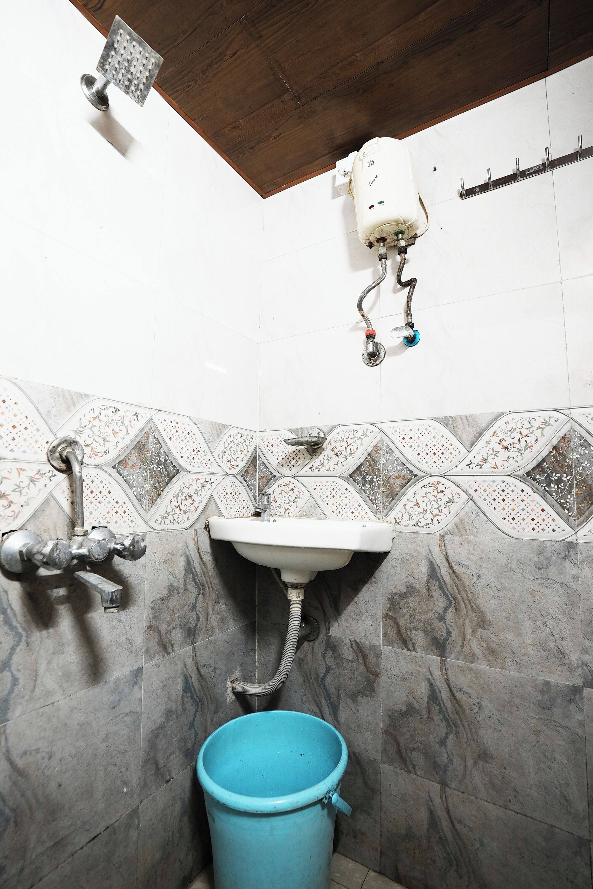 Un baño con ducha, lavamanos y un cubo azul.