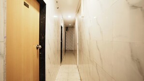 A hallway with marble walls and a wooden door. - Harihara Residency Comfort Andheri East, Mumbai (Mumbai)