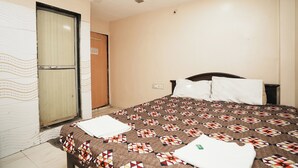 A bedroom with a bed, a ceiling fan, a door, and a wall with a decorative pattern. - Harihara Residency Comfort Andheri East, Mumbai (Mumbai)