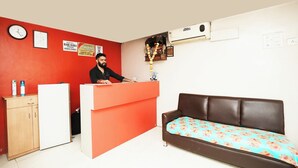 A hotel reception area with a receptionist, a clock, a desk, a couch, and a wall-mounted air conditioner. - Harihara Residency Comfort Andheri East, Mumbai (Mumbai)