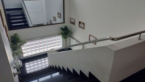 A staircase with a handrail, a large mirror, and framed pictures on the wall. - Bangreng Inn (Bandung)