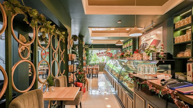 A restaurant with a long counter, a Christmas tree, and a display case with food items. - Bangreng Inn (Bandung)