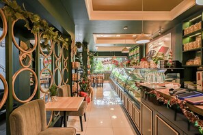 A restaurant with a long counter, a Christmas tree, and a display case with food items. - Bangreng Inn (Bandung)