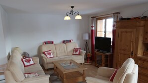 A living room with two sofas, a coffee table, a TV, and a wooden cabinet.