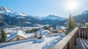A snow-covered mountain village with wooden cabins and a clear sky.